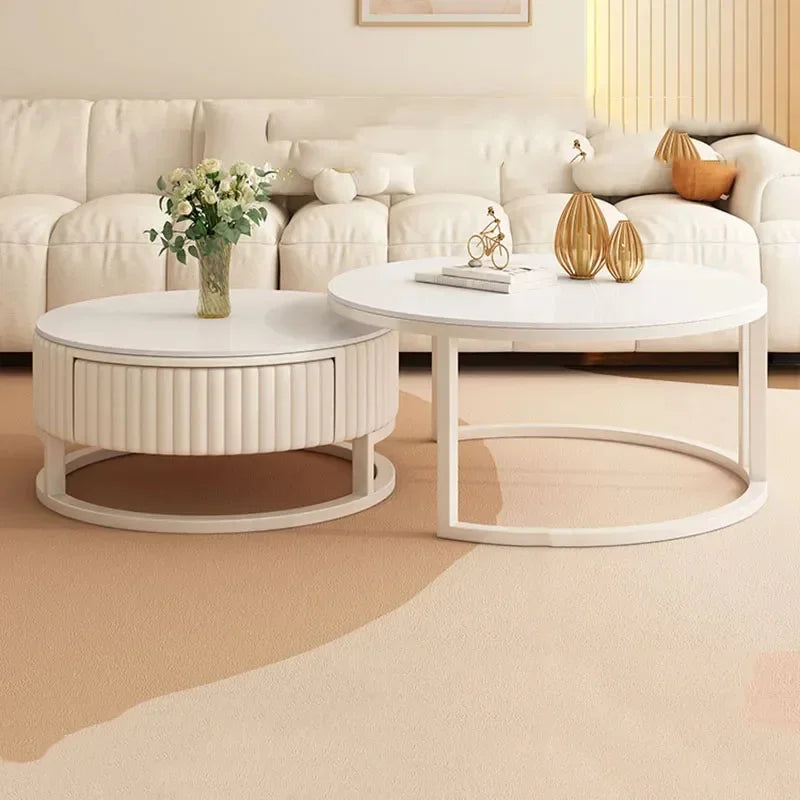The Luxury Round Coffee Table Set with a flower vase and decor sits on a beige carpet before a white sofa, enhancing the modern living room's style.