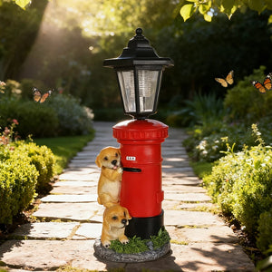 A Solar Dog Light stands on a garden path, styled like a Victorian red post lantern shaped as a mailbox, with two puppy statues at its base and butterflies flying nearby.