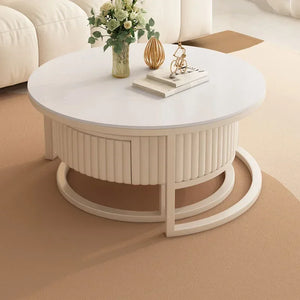 The Luxury Round Coffee Table Set features a minimalist marble-look design and is styled with a decorative vase, books, and ornament on top, all placed on a beige carpet in a modern living room.