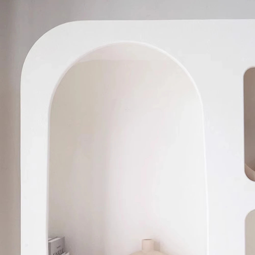 The Minimalist Cream Wind Sculptural Shelf, with its white finish and rounded edges, is partially displayed against a plain wall; a few objects rest on the lower shelf, adding elegance to any modern interior.