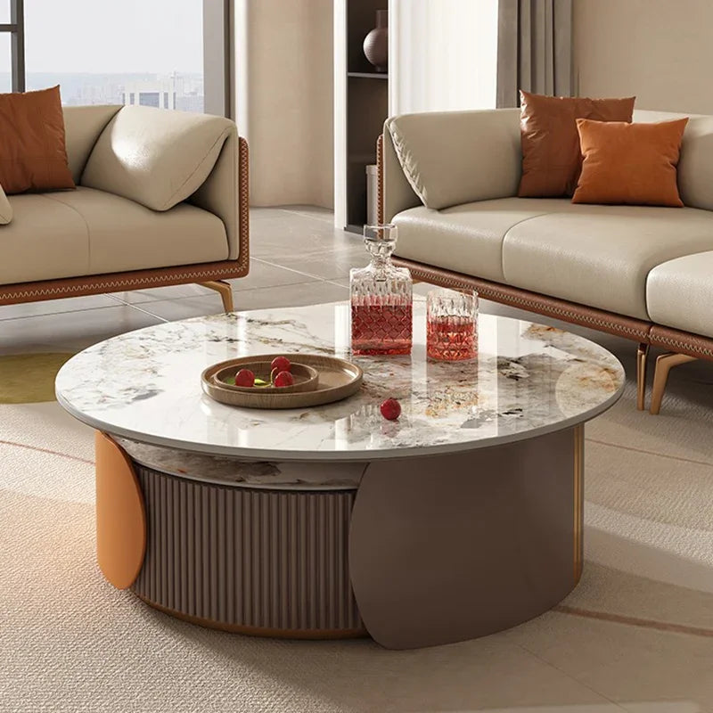 The Luxe Round Coffee Table, topped with drinks and fruit, is positioned between two beige sofas in a modern living room.