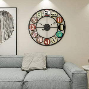 The Nordic Color-Ring Wall Clock with mixed-style numerals hangs above a gray sofa with a beige pillow in a modern living room.