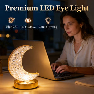 A woman works on a laptop at a desk, illuminated by the Crystal Table Lamp—a crescent moon-shaped LED bedside lamp. Text above highlights features: High CRI, Flicker-Free, Gentle lighting.