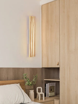 A bedroom corner exudes a calming wooden aesthetic with a Rectangle Wood Wall Light casting ambient LED glow, wooden cabinets, a wooden bed, a small plant, and two decorative figures.