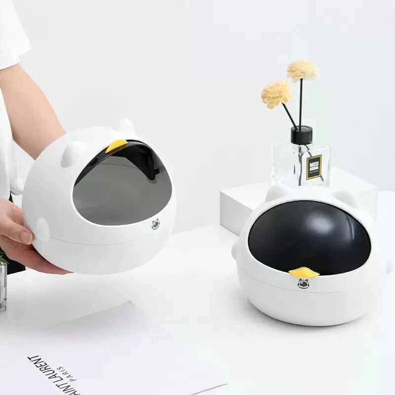 Two white Cute Display SpyCams with black, semi-transparent lids are on a white table—one open and held by a person, the other closed near a vase of yellow flowers.