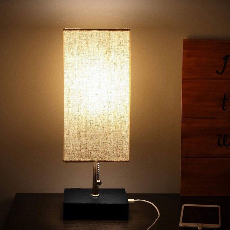 The Desk Lamp Charging SpyCam, with its fabric shade emitting warm light and sleek black base, exudes sophisticated elegance reminiscent of James Bond's world. Its hidden camera feature and phone charging cord add to the clandestine allure on any dark surface.