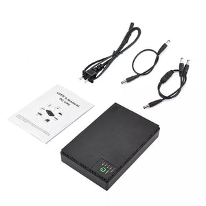 A Portable UPS for WiFi Router in black, ideal for providing backup power, is placed beside an instruction manual, a power cord, and three various connectors on a white background.