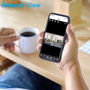 A person holds a smartphone showing the Universal Charger Night Light SpyCam feed, with a cup of coffee on the wooden table in the background.