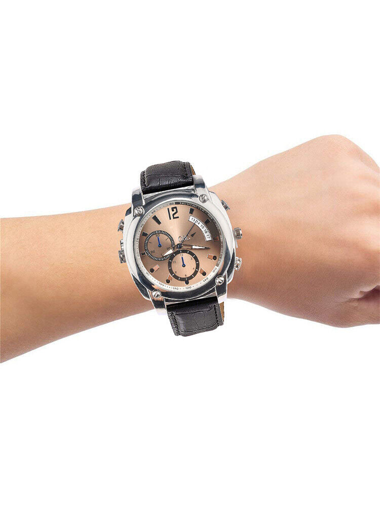 A wrist wearing the Wristwatch SpyCam, a large round silver analog watch with a brown face, black leather strap, and 1080P video recording, shown against a plain white background.