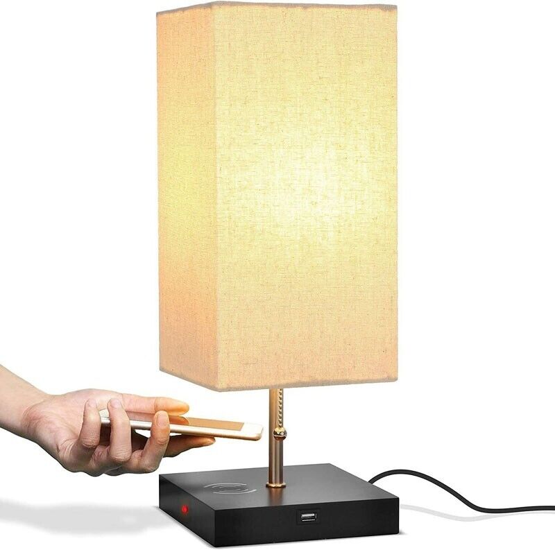 A hand holds a smartphone near a lit Desk Lamp Charging SpyCam inspired by James Bond, featuring a beige shade, black base, and USB port with visible power cord, adding sleek sophistication.