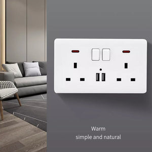 Mounted on a gray wall is the UK Socket SpyCam, a white wall socket featuring USB ports and subtle home surveillance capabilities. The caption reads "Warm, simple and natural." In the background, there's a gray sofa and patterned rug.