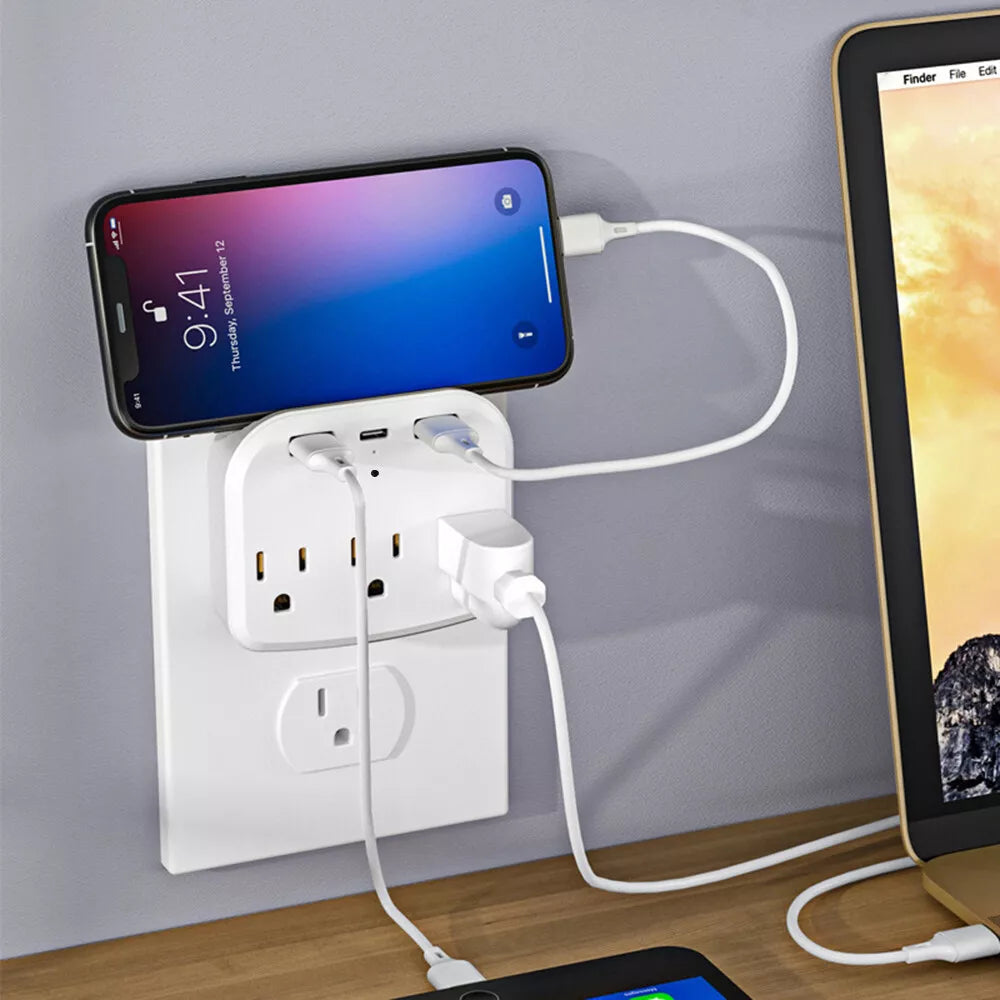 The US Outlet SpyCam is actively charging a phone and a laptop via its multiple USB ports, using white cables. The phone's HD clarity screen displays 9:41, subtly revealing the advanced technology of the US Outlet SpyCam.