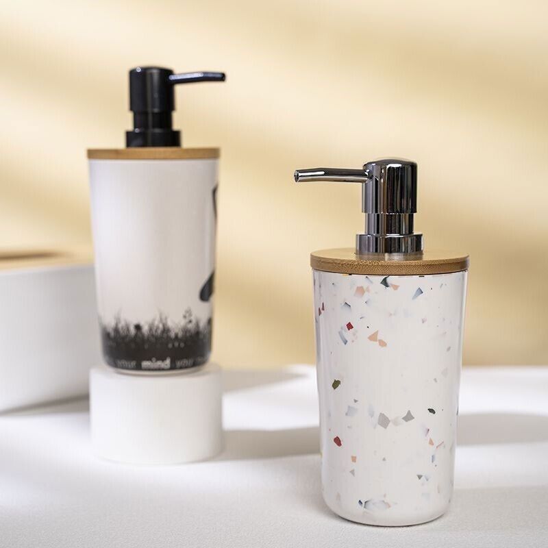 Two Cute Decorative Display SpyCams, disguised as liquid soap dispensers with pump tops and wooden lids, feature hidden 1080P cameras. One is black and white with a nature design, and the other has colorful speckles. Both rest subtly on a white surface for discreet video recording.