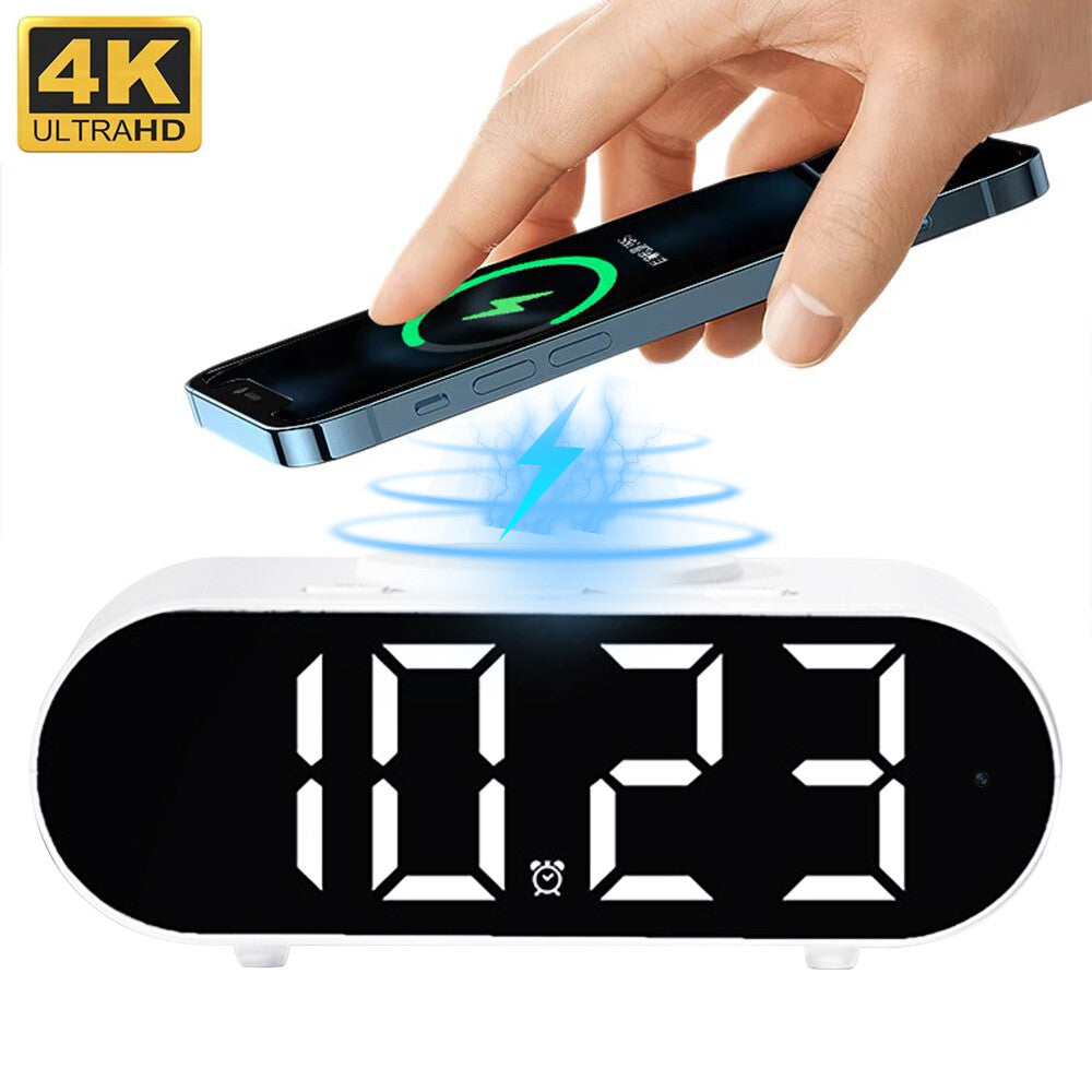 A hand places a smartphone on the Digital Clock Charger SpyCam; phone displays charging. Clock features WiFi surveillance for added security and has a 4K UHD label in the top left corner. Wireless charging symbol is visible.