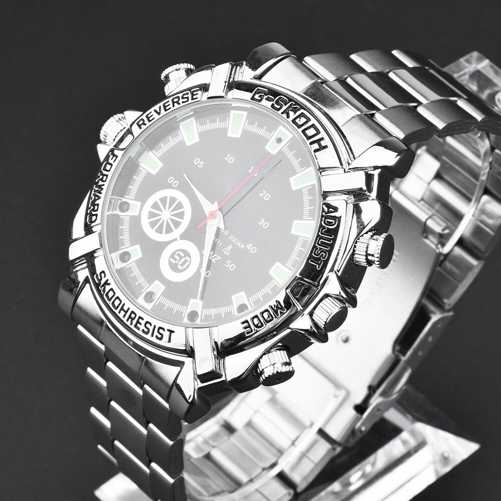 The Watch SpyCam is a silver stainless steel wristwatch with a round dial, multiple buttons, and a labeled bezel, featuring a hidden 1080P camera for discreet video and audio recording. It is displayed on a clear stand against a dark background.