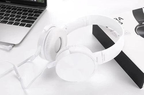 Wired Bass Headphone with an ergonomic design rests on a white surface near a laptop and its box, delivering studio-quality sound.