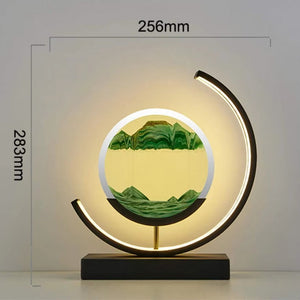 The Sand Timer Lamp features a round decorative design with an illuminated arc and moving sand art at its center, all set on a black base. It measures 256mm in width and stands 283mm tall.