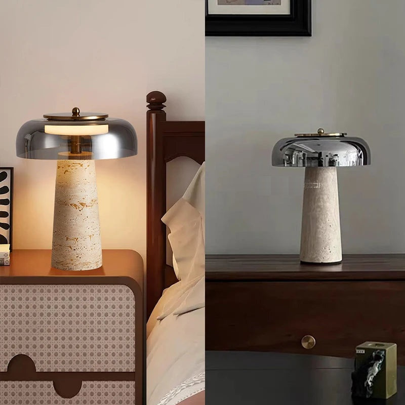 Two stone-based lamps, including a Mushroom Desk Lamp with a metallic dome shade, are placed on wooden tables beside beds in separate rooms—one softly illuminating the space with organic lighting, while the other remains unlit.