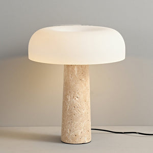 Mushroom Desk Lamp featuring a cylindrical stone base and a white, dome-shaped shade—lit and displayed on a light-colored surface against a plain wall—delivers an elegant, organic touch of lighting to any space.