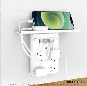 Universal US Outlet SpyCam wall expander with shelf holding a phone and earbuds while charging multiple devices