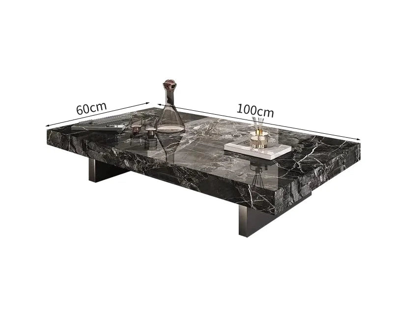 The Modern Luxe Coffee Table features a rectangular black marble top and metal legs, styled with a glass decanter and tray. Ideal for modern interiors. Dimensions: 60 cm x 100 cm.