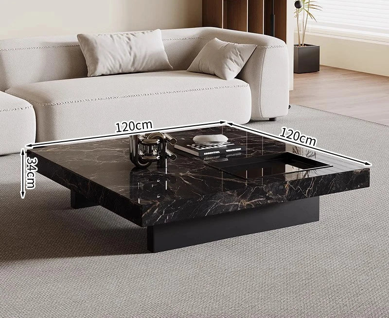 The Modern Luxe Coffee Table, a square black marble minimalist piece measuring 120 x 120 x 34 cm, sits in front of a light-colored sofa—perfect for modern interiors.