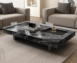 The Modern Luxe Coffee Table, a minimalist black marble piece measuring 130 cm by 60 cm, sits between two beige sofas, bringing elegance to modern living room interiors.
