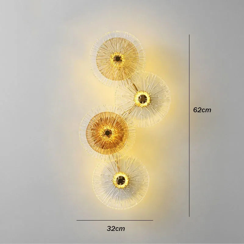 Amber Deco Wall Sconce features four circular, radiating glass discs in a wall-mounted LED design, illuminated from behind. The fixture measures 62 cm in height and 32 cm in width.
