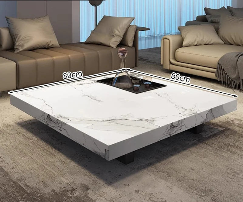 The Modern Luxe Coffee Table, a square marble piece (80cm per side) with a recessed center for glassware, is ideal for modern interiors and fits elegantly between two sofas in the living room.