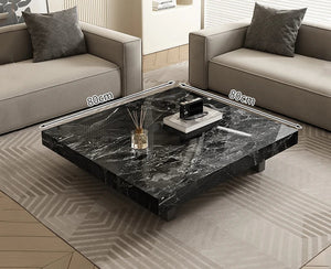 The Modern Luxe Coffee Table, a square black marble minimalist piece measuring 80 cm per side, is placed between two beige sofas in a modern living room.