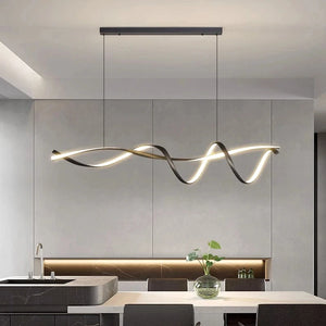 A modern kitchen with a Stylish Pendant Light artistically hanging above a stone island countertop. Adorning the surface are a sink and a plant in a vase, while gray cabinetry and ambient lighting complete the minimalist design.