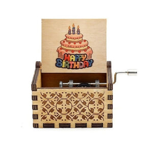 A hand-cranked Happy Birthday Music Box crafted from wood, featuring intricate carvings and an open lid that displays a "Happy Birthday" message alongside an illustration of a cake with candles.