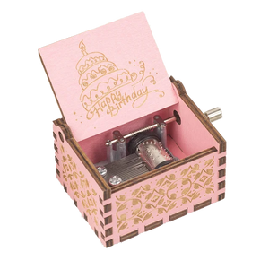 The Happy Birthday Music Box is a small, pink, wooden music box adorned with a "Happy Birthday" message and a charming decorated cake design. Upon opening, it reveals the internal winding mechanism. This delightful hand-cranked music box brings a nostalgic touch to any celebration.