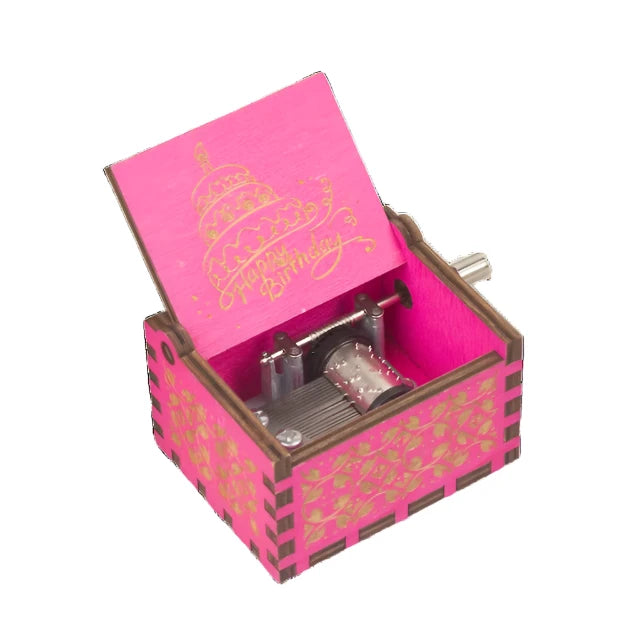 The Happy Birthday Music Box is a small, pink wooden music box featuring floral patterns on the exterior and a "Happy Birthday" design inside the lid. It elegantly showcases its mechanical components, making it an ideal and charming birthday gift.