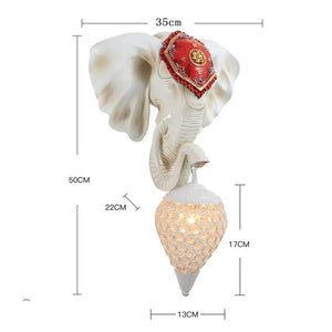 The 3D Elephant Wall Light features a detailed red headpiece and woven hanging light fixture creating a unique ambiance. It measures 50cm tall, 35cm wide, with a base diameter of 13cm, making it an enchanting Elephant Head sculpture.