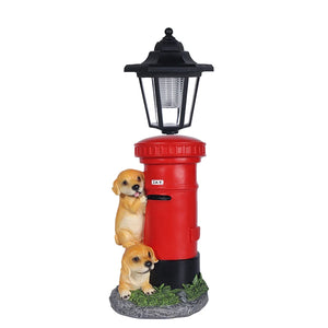 Two small Solar Dog Light figurines stand beside a red postbox topped with a vintage-style street lamp, all arranged on a grassy base.