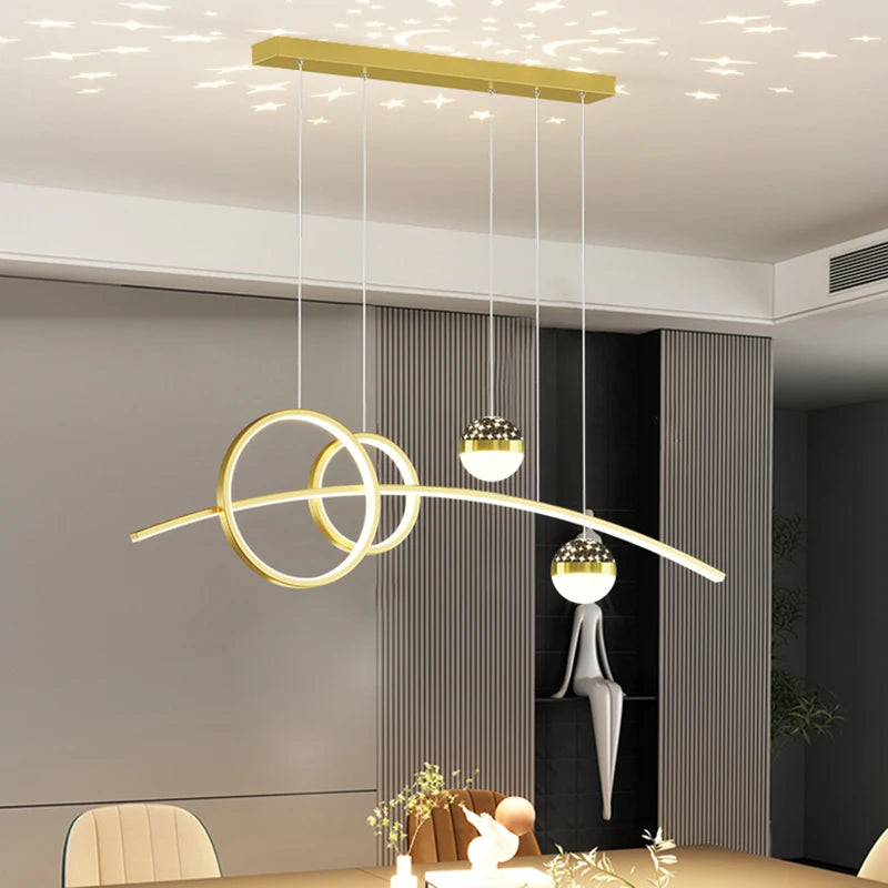 A modern dining room showcases the Stellar Pendant Light with geometric rings and spherical bulbs above a table adorned with decorative items, enhanced by celestial beige and gray tones in a neutral color palette.
