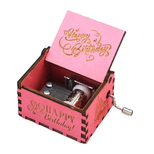 The Happy Birthday Music Box is a charming pink wooden music box with "Happy Birthday" engraved on the lid and sides. When the lid is opened, it reveals a hand-crank music mechanism inside—an ideal birthday gift to celebrate a special day.