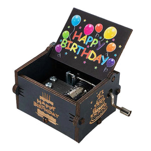 A black Happy Birthday Music Box with an open lid revealing vibrant balloons and "Happy Birthday" text. This wooden music box features a hand-cranked wind-up mechanism and is adorned with a cheerful "Happy Birthday" design on the sides.