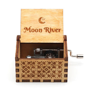 The Wooden Music Box is a hand-cranked, wooden treasure featuring an open lid inscribed with "Moon River" and adorned with a crescent moon. Its intricate carved patterns make it perfect for those who cherish classic melodies and handcrafted music boxes.