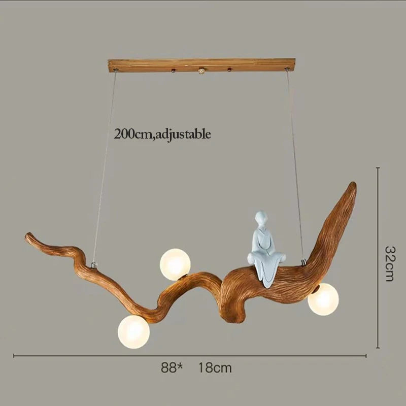 Discover the Zen-Inspired Wooden Pendant Light, featuring a handcrafted wooden ceiling fixture with three round bulbs in a branch-like design and a small person sculpture. Dimensions: 88 x 32 x 18 cm; adjustable length up to 200 cm.