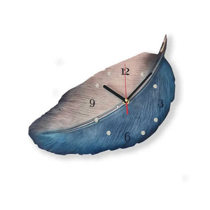 The Wooden Grain Wall Clock showcases a modern feather-shaped motif, offering an organic touch with one side in silver and the other in blue. This wood wall clock is equipped with black hands and prominently displays the numbers 3, 6, 9, and 12 for easy readability.