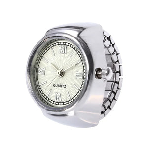 The Eternal Ring Watch features a minimalist white dial with black Roman numerals, "QUARTZ" display, and a sleek silver stretch band—combining unique jewelry style with modern elegance.