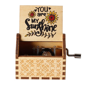 The Music Box - You Are My Sunshine is a romantic keepsake featuring a rotary handle with a hand-crank mechanism. When the lid is open, it reveals an inscription that reads "You Are My Sunshine," surrounded by sunflower decorations. The wooden box boasts intricate carved patterns, adding to its charm and making it a delightful treasure.