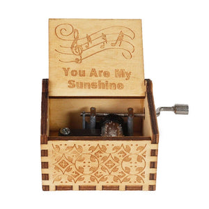 The "Music Box - You Are My Sunshine" is a romantic wooden music box featuring a hand-cranked rotary handle. It showcases an open lid engraved with "You Are My Sunshine" and music notes, along with intricate carvings on the sides.