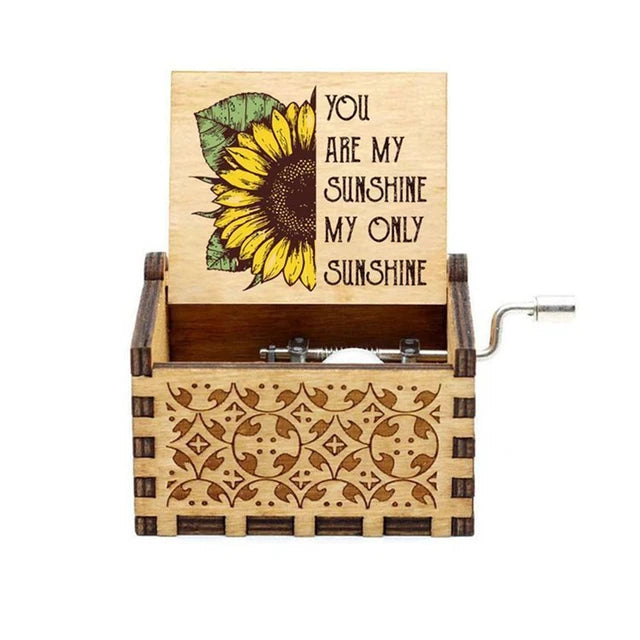 The "Music Box - You Are My Sunshine" is a wooden hand-crank music box adorned with a sunflower design, playing the timeless melody "You Are My Sunshine" and featuring the text "You are my sunshine, my only sunshine.