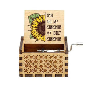 The "Music Box - You Are My Sunshine" is a wooden hand-crank music box adorned with a sunflower design, playing the timeless melody "You Are My Sunshine" and featuring the text "You are my sunshine, my only sunshine.