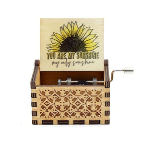 The Music Box - You Are My Sunshine is a wooden hand-crank music box with an open lid that features a sunflower illustration and the text "You are my sunshine, my only sunshine." This romantic rotary handle music box plays a classic melody, adding a touch of heartfelt charm.