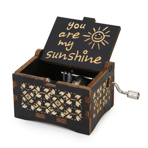 Introducing the "Music Box - You Are My Sunshine," a small, ornate black wooden music box featuring a romantic rotary handle and an open lid that displays the text "You Are My Sunshine" along with a charming sun drawing.