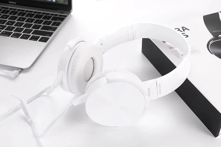Wired Bass Headphone rests on a white surface near a laptop and its box, featuring studio-quality sound, ergonomic design, and a partially coiled visible cable.